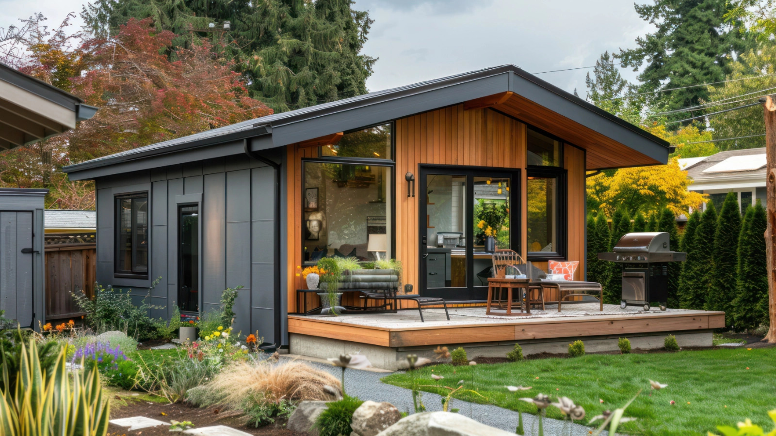 Modern detached accessory dwelling unit with dark siding, warm wood cladding, large windows, and a covered patio