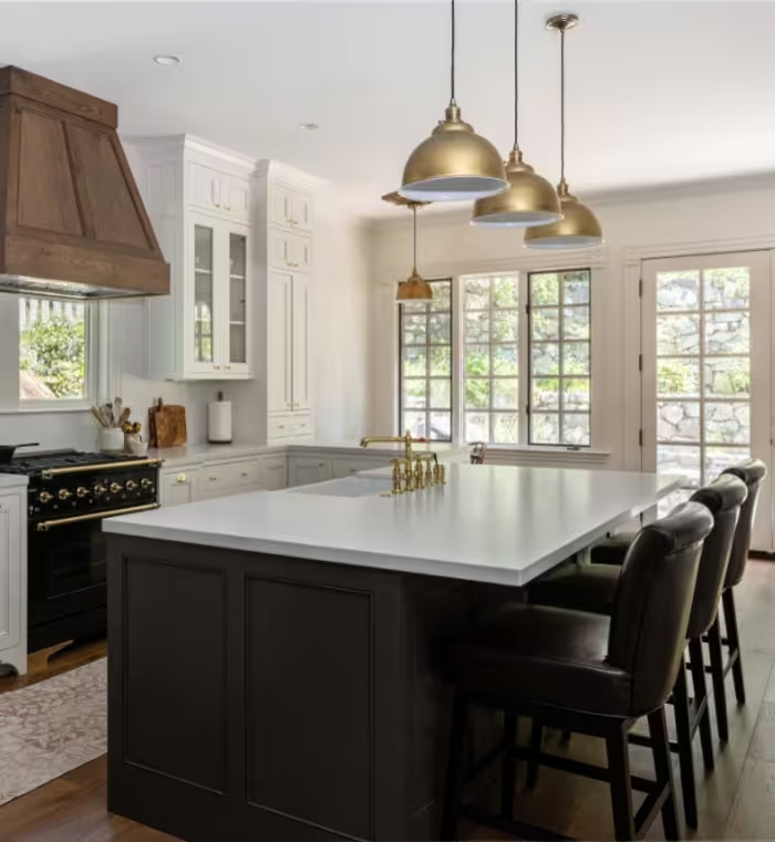 The finished kitchen: white cabinetry, a custom wood hood, and a central island opening toward the garden