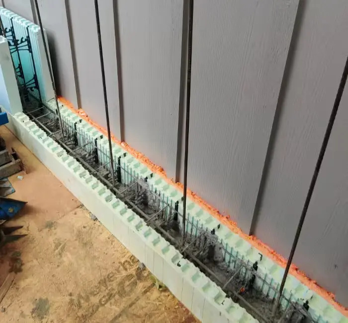 Open insulated-concrete wall showing vertical steel reinforcement set into the concrete core