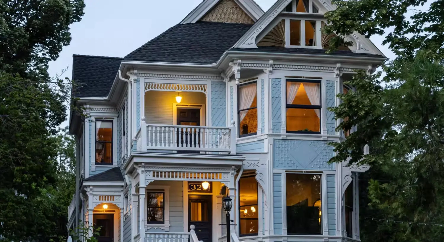 Historic Victorian home in downtown Nevada City, lit at twilight behind a white picket fence